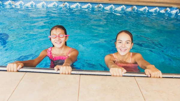 Retrato de dos adolescentes sonrientes nadando en la piscina. Familia divirtiéndose y relajándose en el agua en las vacaciones de verano —  Fotos de Stock