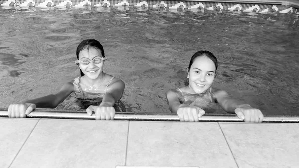 Ritratto in bianco e nero di due felici adolescenti sorridenti in posa in piscina coperta — Foto Stock