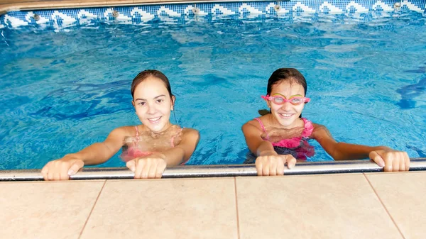 Portret van twee gelukkig glimlachende tiener meisjes in de indoor zwembad — Stockfoto