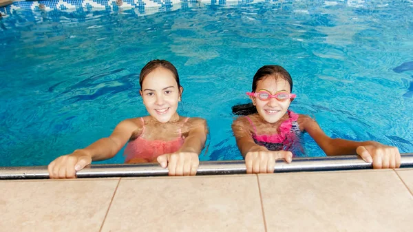 Retrato de dos adolescentes sonrientes nadando en la piscina. Familia divirtiéndose y relajándose en el agua en las vacaciones de verano —  Fotos de Stock