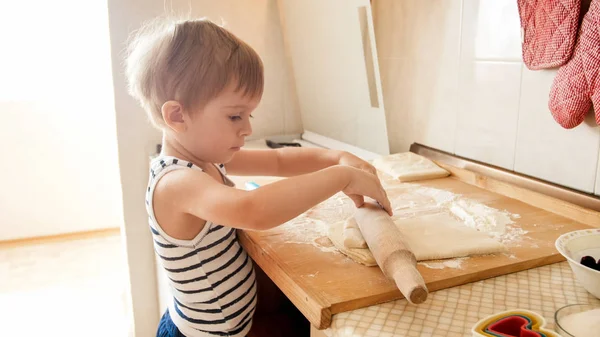 Ritratto di bambino che fa la pasta su tavola da cucina in legno. Torte o biscotti da forno per bambini — Foto Stock