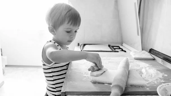 Ritratto in bianco e nero di adorabile bambino di 3 anni che cucina biscotti sulla cucina. Cottura per bambini e cottura in cucina per la prima colazione — Foto Stock