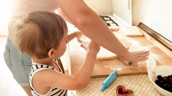 Portrét mladé usmívající se matky, která učí, jak jí tři roky pečovat a dělat sušenky v kuchyni — Stock fotografie