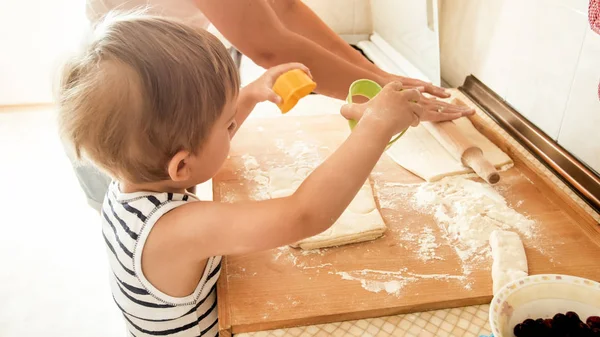 Portret van moeder met 3 jaar peuter zoon bakken koekjes op de keuken in de ochtend. Familie bakken en koken thuis — Stockfoto