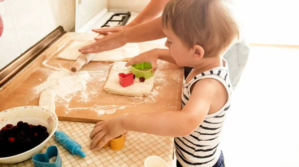 Ritratto di giovane madre sorridente che insegna al suo bambino di 3 anni a cucinare e fare biscotti in cucina — Foto Stock