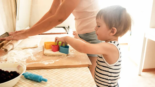 Retrato de la madre con 3 años hijo pequeño hornear galletas en la cocina por la mañana. Hornear en familia y cocinar en casa —  Fotos de Stock