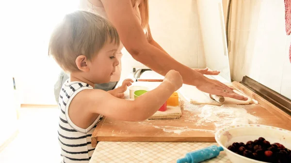 Ritratto di giovane bella donna che insegna al suo bambino a fare biscotti e cuocere torte in cucina a casa — Foto Stock