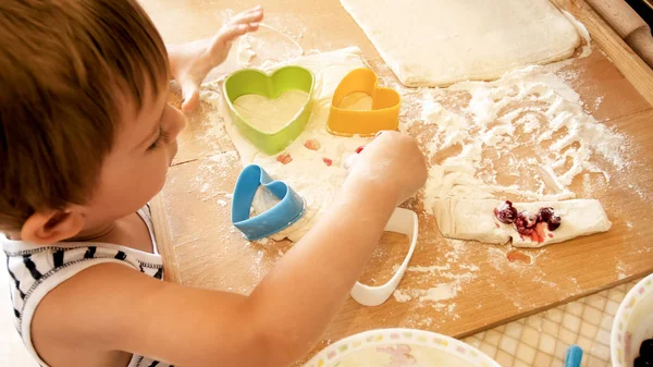 Портрет 3-летнего мальчика, стоящего на кухне и готовящего тесто. Детская выпечка и завтрак — стоковое фото