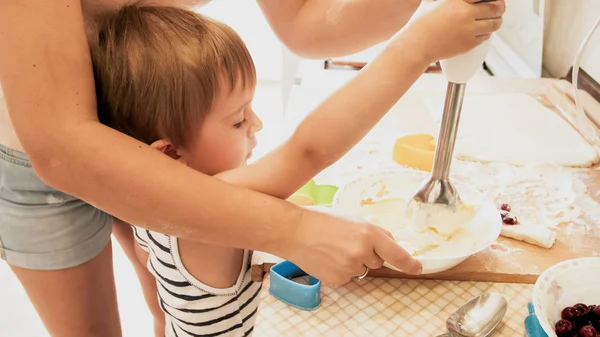 Retrato de niño sonriente feliz con madre joven horneando y cocinando en la cocina. Enseñanza y educación de los padres en el hogar — Foto de Stock