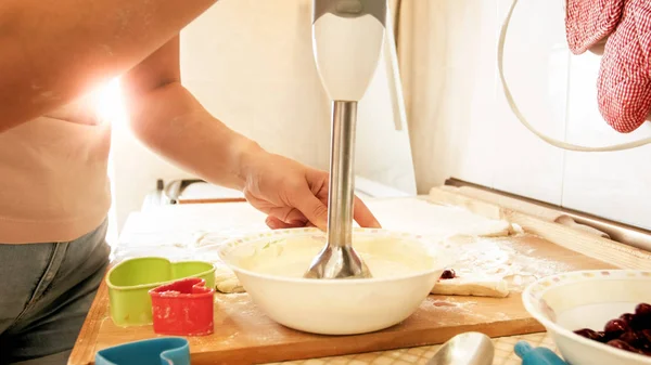 Image rapprochée de jeune femme utilisant un mélangeur électrique pendant la cuisson et la cuisson sur la cuisine tôt le matin ensoleillé — Photo