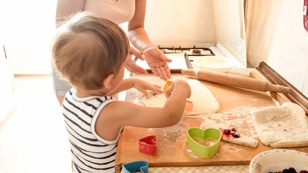 Genç anne pişirme ve mutfakta pişirme ile mutlu gülümseyen yürümeye başlayan çocuk Portresi. Evde ebeveyn öğretimi ve eğitilmesi — Stok fotoğraf