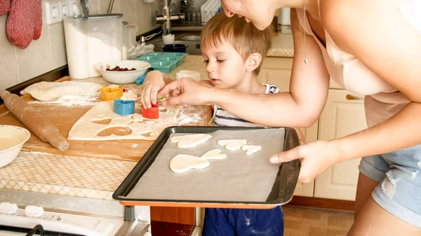 Portrait of cute little boy with young mother baking cookies on baking pan at dapur — Stok Foto
