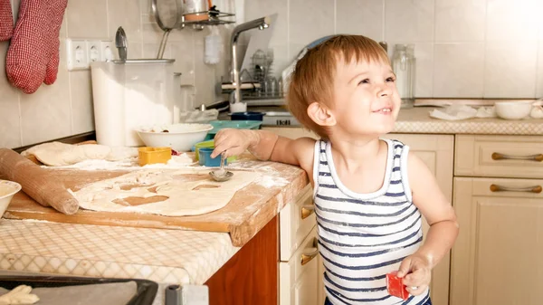 Porträt eines kleinen lächelnden Jungen, der zu Hause auf Kisten kocht. Kind backt und macht Teig — Stockfoto