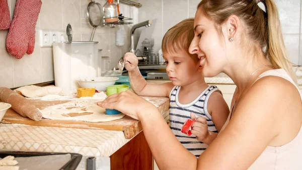Portrait of cute little boy with young mother baking cookies on baking pan at dapur — Stok Foto