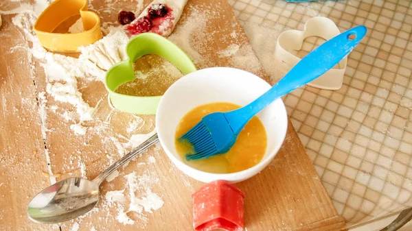 Foto de cerca de masa fresca, huevos, leche, y un montón de herramientas para la panadería y la cocina acostado en el mostrador de la cocina de madera grande —  Fotos de Stock