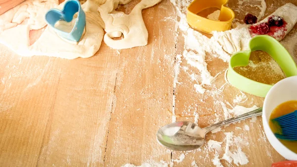 Foto de close-up de massa fresca, ovos, leite e muitas ferramentas para padaria e cozinhar deitado no grande balcão de cozinha de madeira — Fotografia de Stock