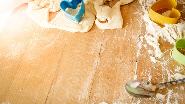 Vista de cerca desde un ángulo alto en un escritorio de madera cubierto con harina, masa, herramientas de cocina e ingredientes para cocinar y hornear en la cocina — Foto de Stock