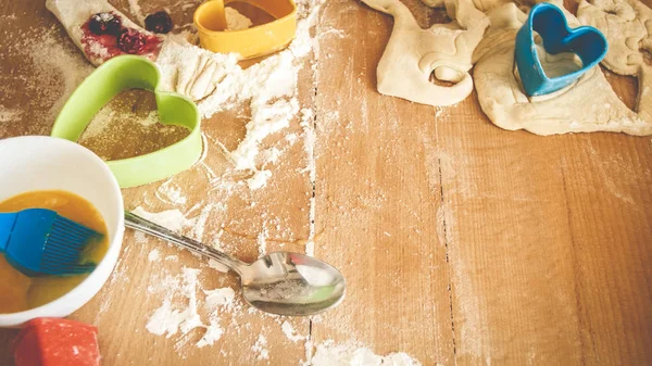 Foto de cerca de masa fresca, huevos, leche, y un montón de herramientas para la panadería y la cocina acostado en el mostrador de la cocina de madera grande — Foto de Stock