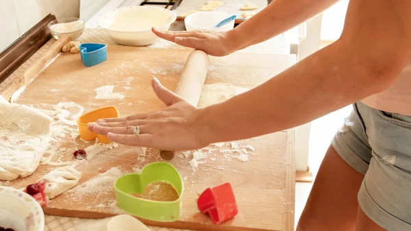 Closeup image of young woman rolling dough with wooden rolling pin. Housewife making pizza at home on kitchen — Stock Photo, Image
