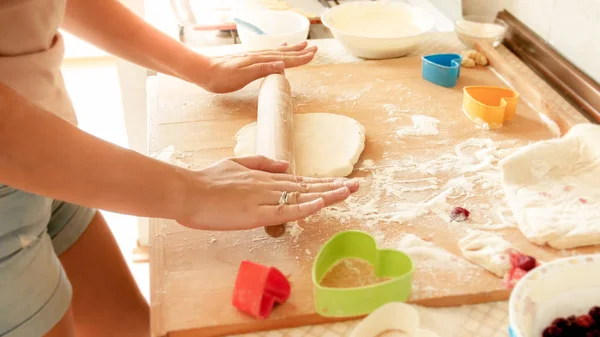 Closeup image of young woman rolling dough with wooden rolling pin. Housewife making pizza at home on kitchen — Stock Photo, Image