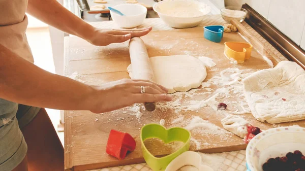 View from the top on young woman making dough and rolling it with wooden rolling pin on kitchen counterboard — Stock Photo, Image