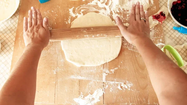 Photo rapprochée d'une jeune femme fabriquant de la pâte pour pizza. Pâte à rouler femme au foyer avec rouleau en bois — Photo