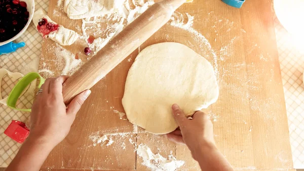 Imagen de primer plano de la mujer joven rodando masa con rodillo de madera. Ama de casa haciendo pizza en casa en la cocina — Foto de Stock