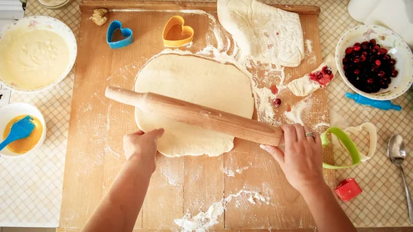 年轻女子用木滚针滚动面团的特写图像。家庭主妇在家厨房做比萨饼 — 图库照片