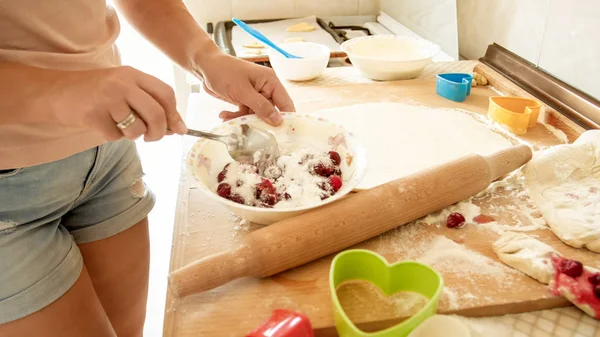 Image rapprochée de la jeune femme au foyer versant du sucre dans un grand bol avec des baies de fgresh tout en faisant de la sauce pour tarte — Photo