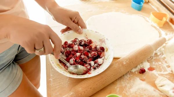 Imagen de primer plano de una mujer joven mezclando azúcar con bayas. Ama de casa haciendo salsa de bayas para pastel dulce — Foto de Stock