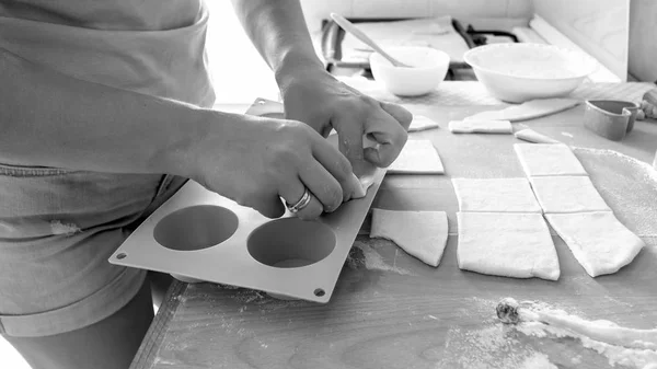 Черно-белый образ молодой женщины, делающей кексы в силиконовой форме на кухне — стоковое фото