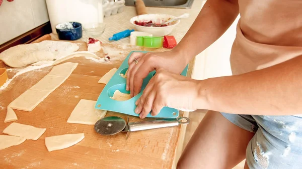 Крупный план фотографии молодой женщины, которая печет кексы дома. Домохозяйка кладет куски теста в силиконовую форму — стоковое фото