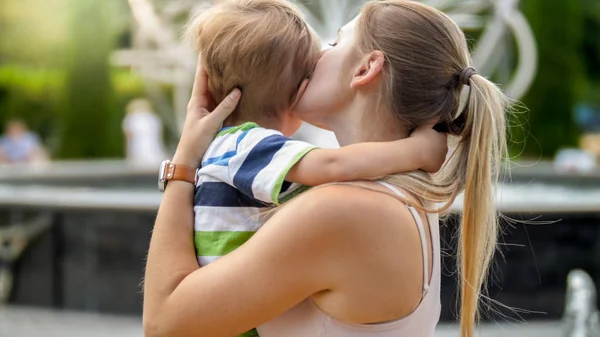 Close-up portret van jonge moeder knuffelen en strelen haar huilen weinig kind jongen in Park — Stockfoto