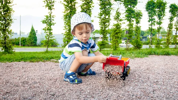 모래와 함께 놀고 사랑스러운 3 살 짜리 유아 소년의 사진과 공원에서 트럭과 트레일러. 모래밭에서 파고 건물 — 스톡 사진