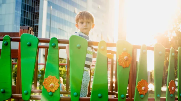 Portret 3-letniego małego chłopca spacerowego i indeksowania na wysokim drewnianym moście na placu zabaw dla dzieci w parku. Dzieci bawią się i bawią na placu zabaw — Zdjęcie stockowe