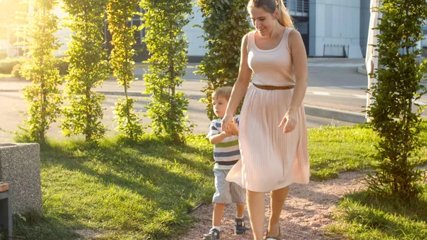 Imagen de una madre joven y feliz con un hijo pequeño de 3 años jugando y corriendo en el parque infantil —  Fotos de Stock