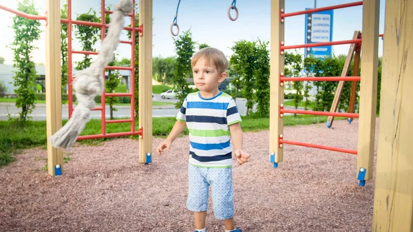 Retrato de 3 anos de idade brincando no playground e tentando subir na corda grande no parque — Fotografia de Stock