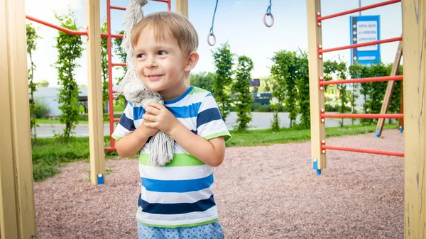 Retrato de niño sonriente feliz jugando con una cuerda grande para escalar en el palyground de los niños en el parque. Niños activos y deportivos divirtiéndose y jugando —  Fotos de Stock