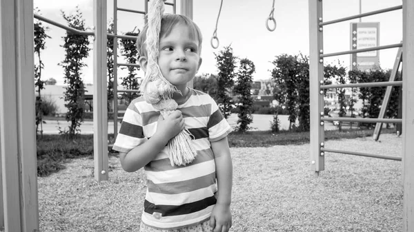 Porträt eines glücklich lächelnden Kleinkindes, das mit einem großen Seil spielt, um auf dem Kinderspielplatz im Park zu klettern. Aktive und sportliche Kinder mit Spaß und Spiel — Stockfoto