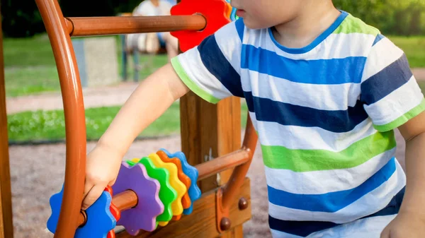 Closeup image of little boy playing on the playground and rotating wooden rings. Smarts child solving puzzle and learning how to count — Stock Photo, Image