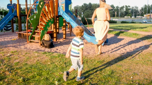 公園の子供の遊び場で遊んで走っている3歳の小さな息子と幸せな若い母親のイメージ — ストック写真