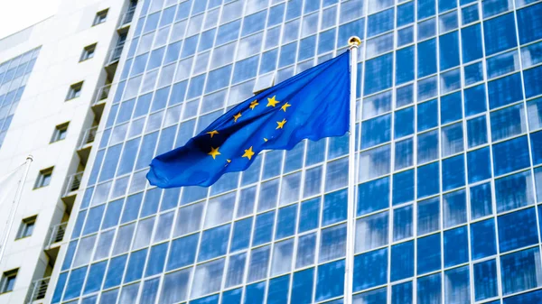 Image of European Union flag with staras over blue background against big modern office building. Concept of ecenomy, development, government and politics — Stock Photo, Image