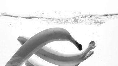 Taze olgun banas düşen ve sıçrama closeup siyah beyaz görüntü. Suda yüzen lezzetli meyveler