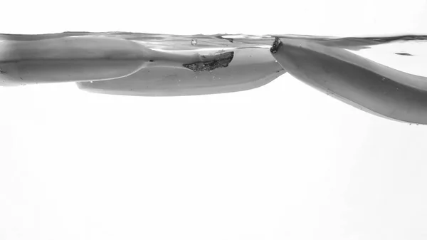 Zbliżenie czarno-białego wizerunku świeżych dojrzałych Banas spada i rozpryskiwania. Smaczne owoce pływające w wodzie — Zdjęcie stockowe