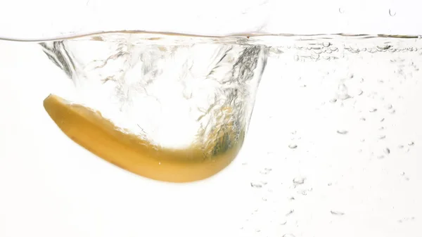 Imagen de primer plano de plátanos frescos maduros cayendo y salpicando en agua contra fondo blanco aislado — Foto de Stock