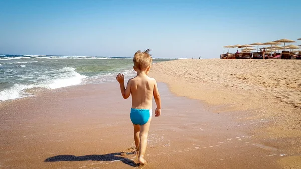 Widok z tyłu obraz mały 3 lat chłopiec maluch chodzenie na mokrej plaży piasku morza — Zdjęcie stockowe