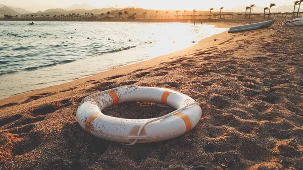 Κοντινά πλάνα, η εικόνα του δακτυλίου που σώζει τη ζωή, βρίσκεται στη θάλασσα. Υπέροχο ηλιοβασίλεμα πάνω από τον ωκεανό — Φωτογραφία Αρχείου