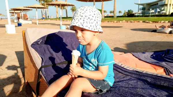 Portret małego 3-letniego chłopca jedząc lody na piaszczystej plaży morskiej. Dziecko relaks na letnich wakacji wakacje na plaży — Zdjęcie stockowe