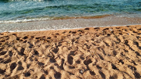 Крупный план спокойных морских волн, катящихся по мокрому песку на морском пляже — стоковое фото