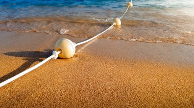 Denizde yüzen ve kumlu plajda yatan halat ile bağlı yüzen şamandıralar uzun çizgi Closeup güzel görüntü